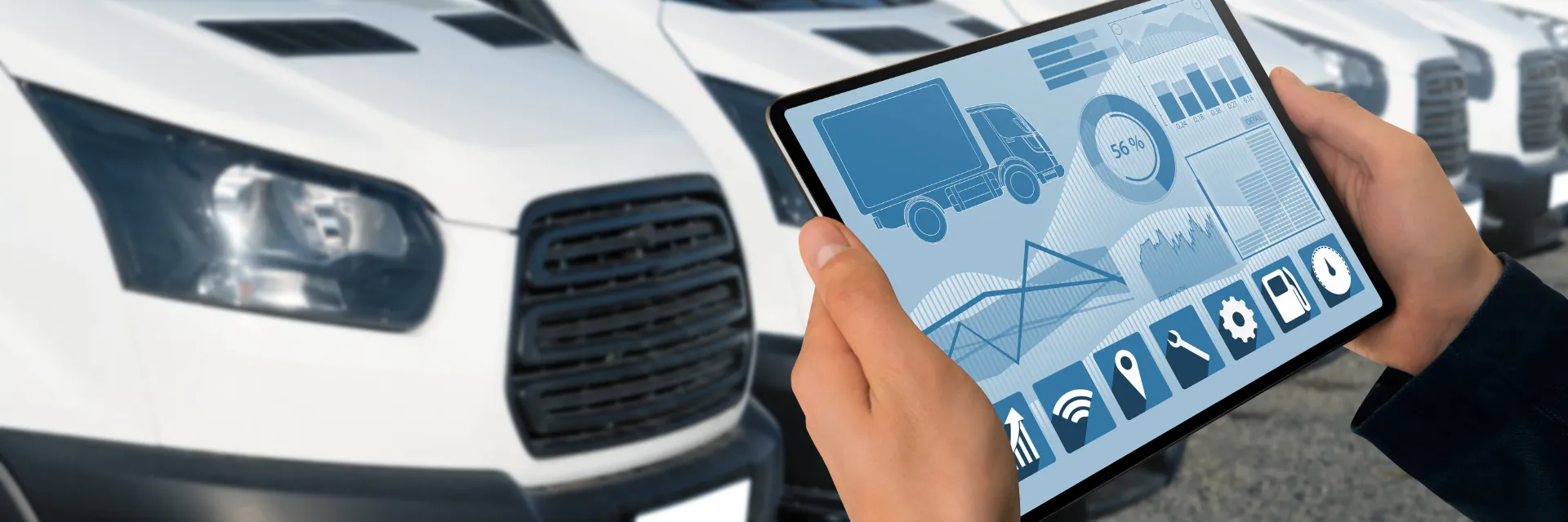manager with a digital tablet in front of a row of fleet vans