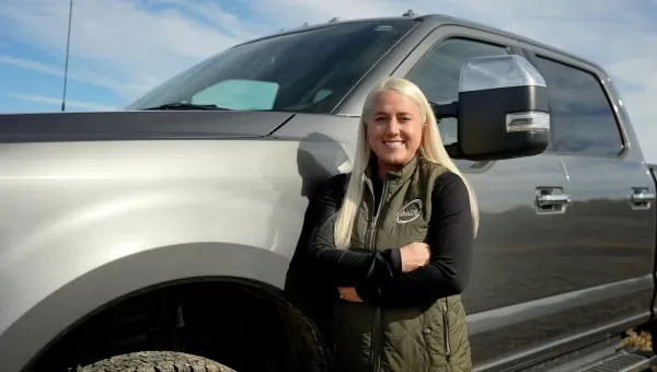 Smiling woman standing beside a gray Ford pickup truck